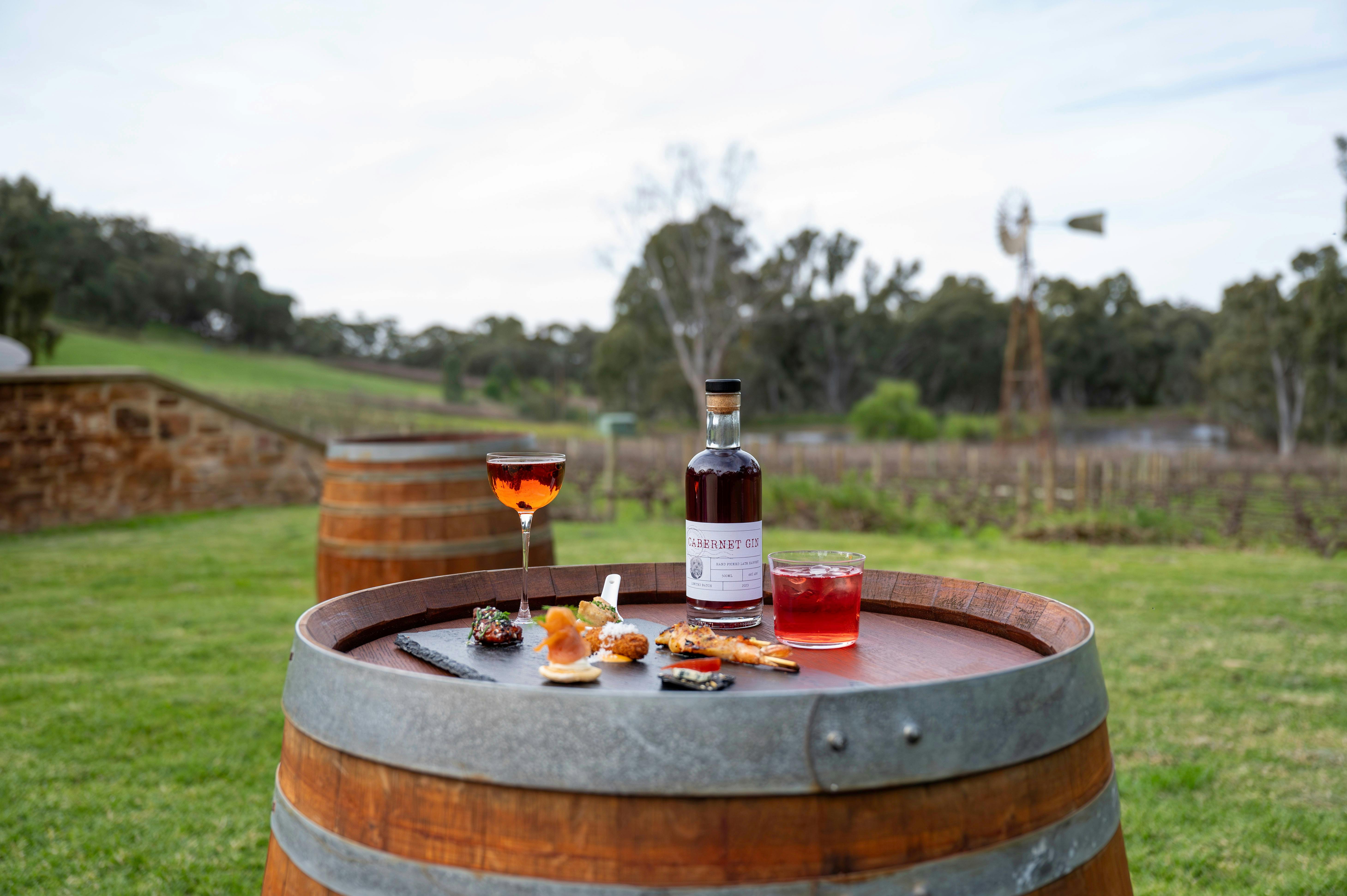 A wine barrel with food and drinks with vineyard & windmill in the background