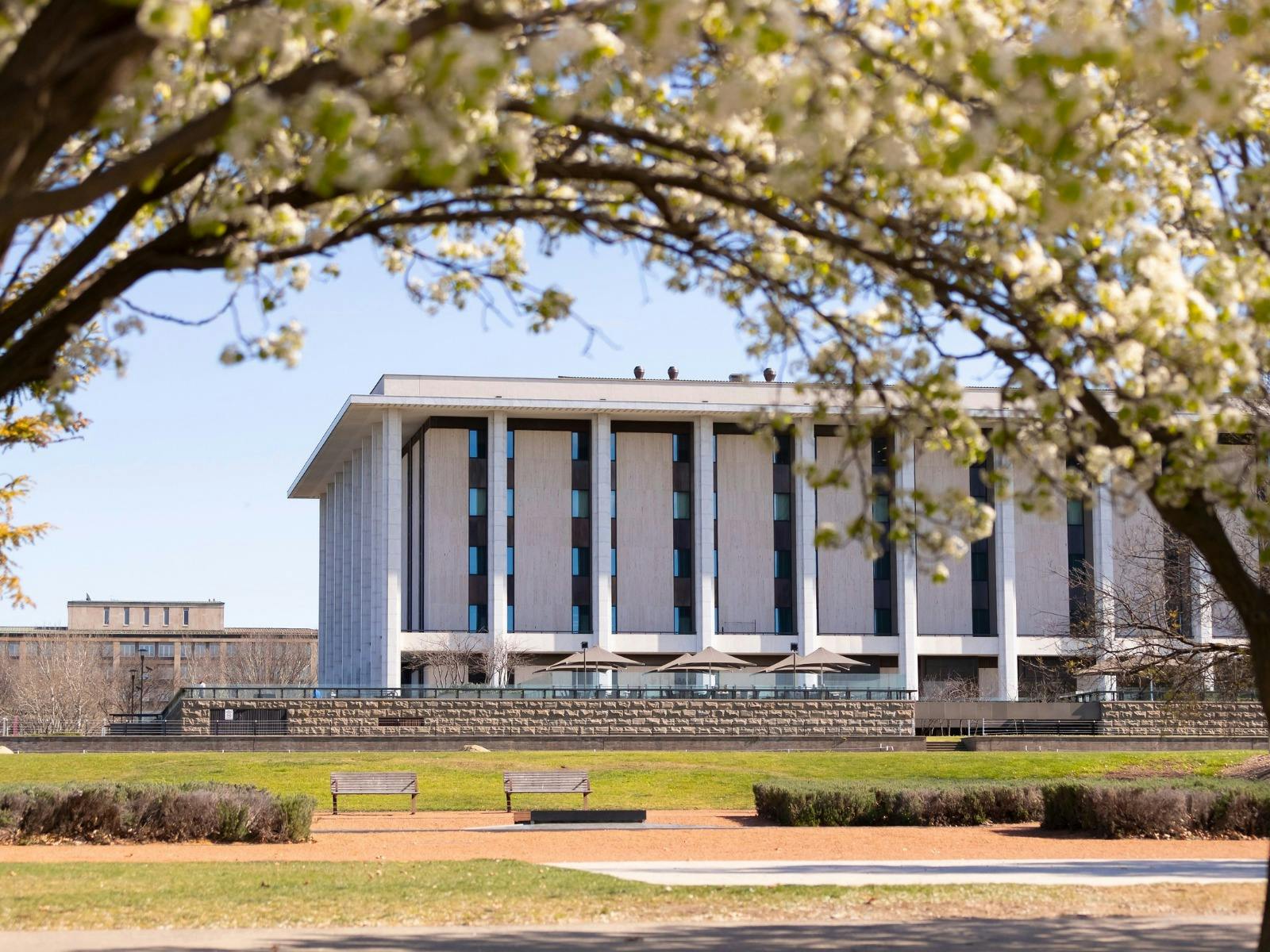 The National Library of Australia building with park benches and trees in the image.