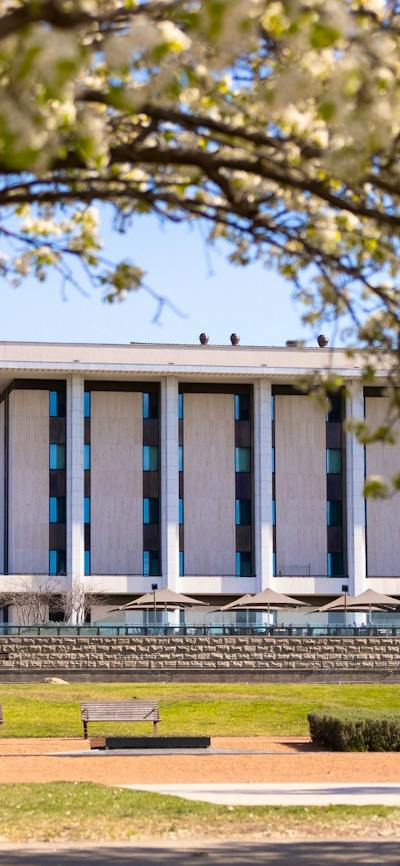 The National Library of Australia building with park benches and trees in the image.