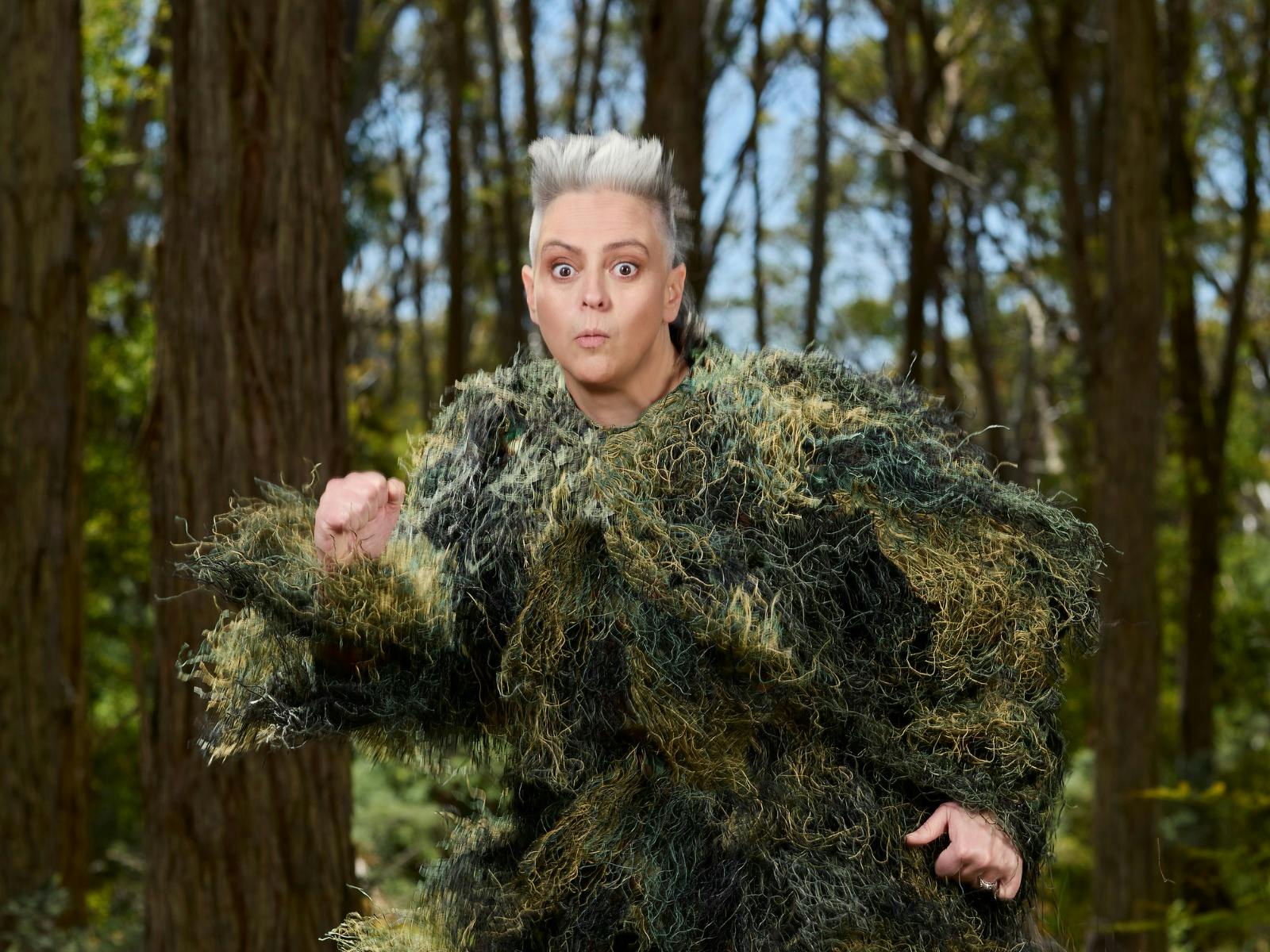 Woman in a ghillie suit running through the forest