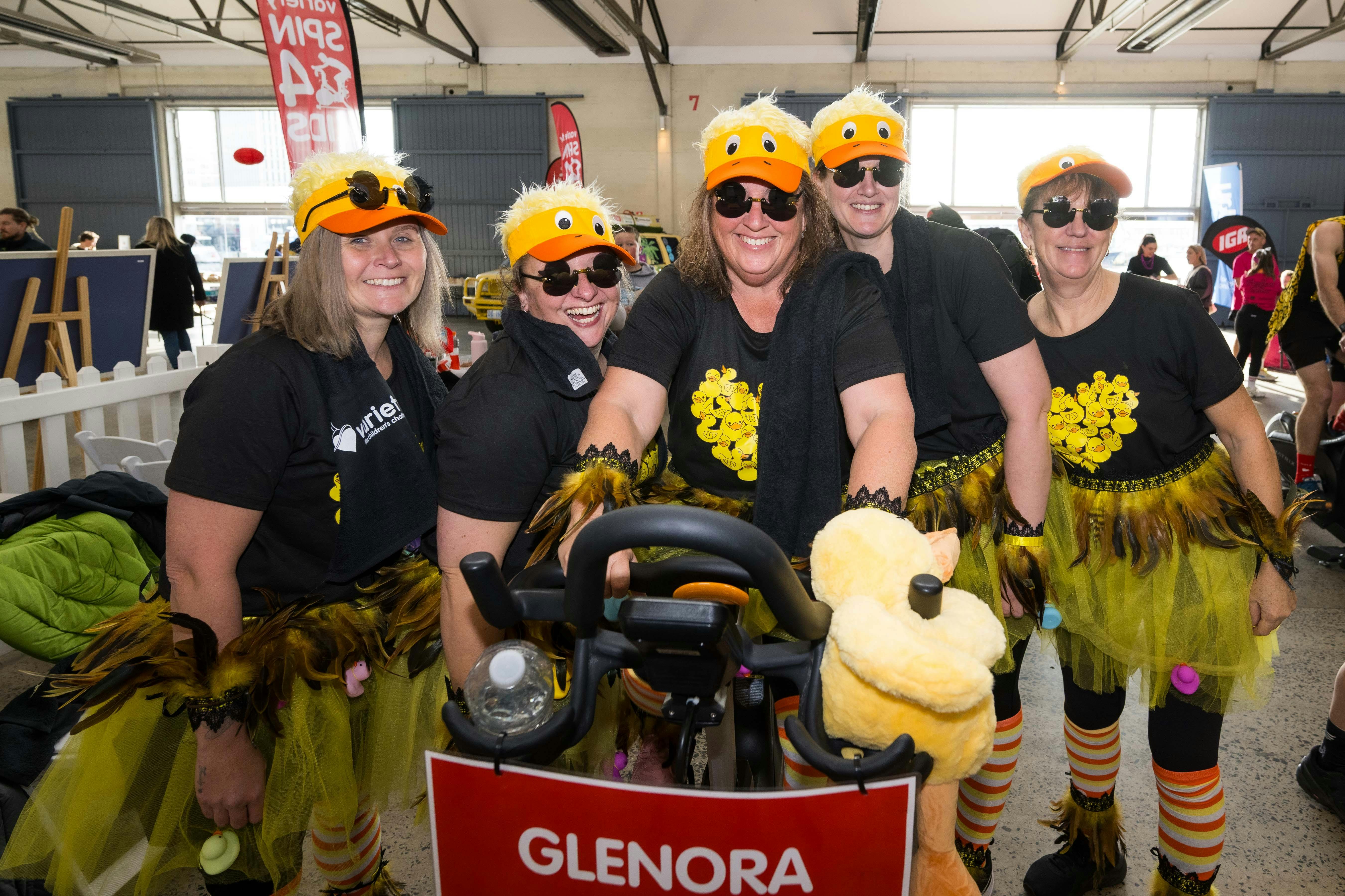 costumed ladies dressed like fluffy yellow ducks on a spin bike at Spin4Kids event