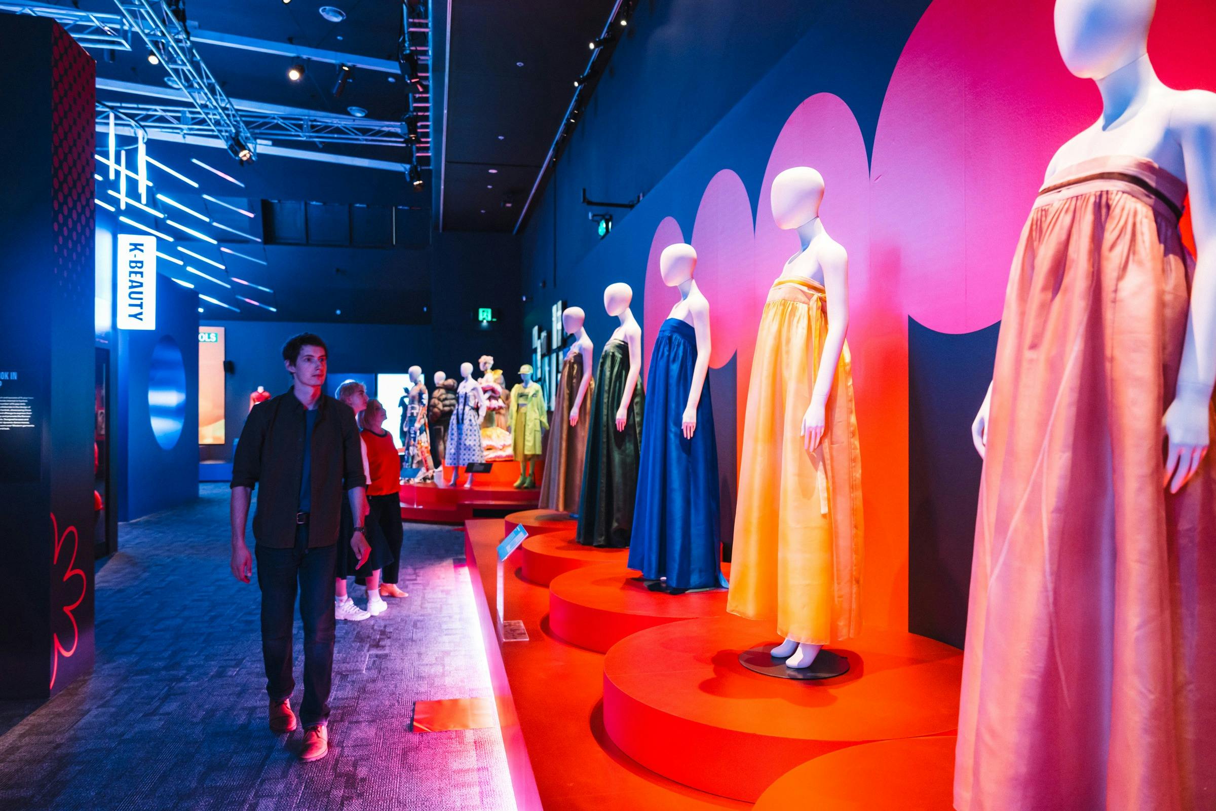 Korean fashion being displayed on mannequins with a young man walking alongside the display.