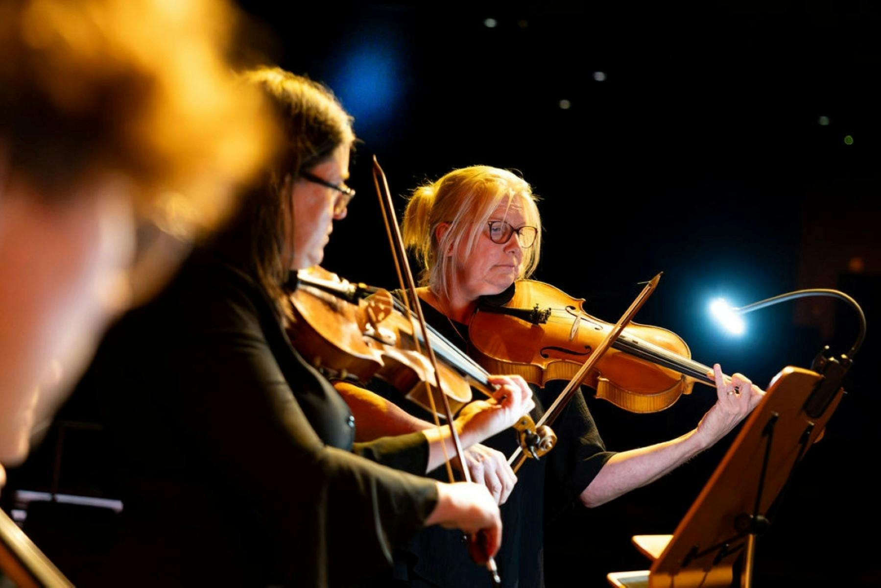Two women playing their instruments on stage