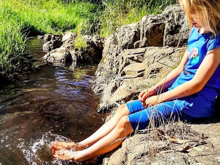 Girl dipping her feet in little creek.