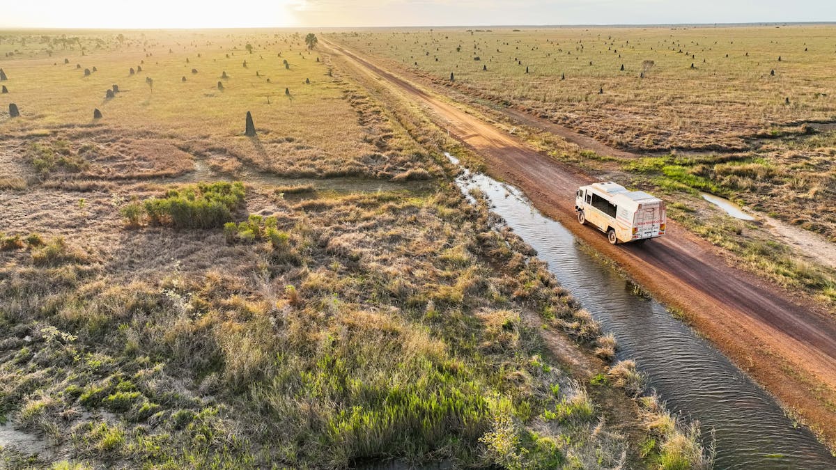 truck driving on dirt road with termite mounds