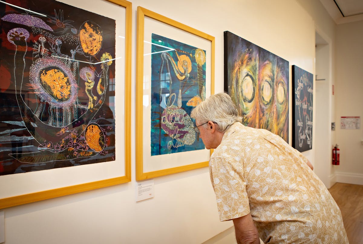 Man looking at Arone Meeks paintings inside the Court House Gallery