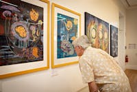 Man looking at Arone Meeks paintings inside the Court House Gallery