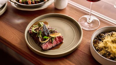 Wagyu flank + garlic butter, served with a glass of red wine, a side of carrots, and sprouts