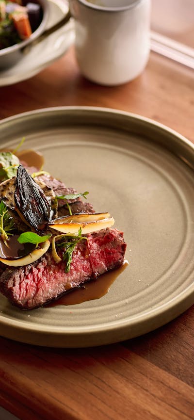 Wagyu flank + garlic butter, served with a glass of red wine, a side of carrots, and sprouts