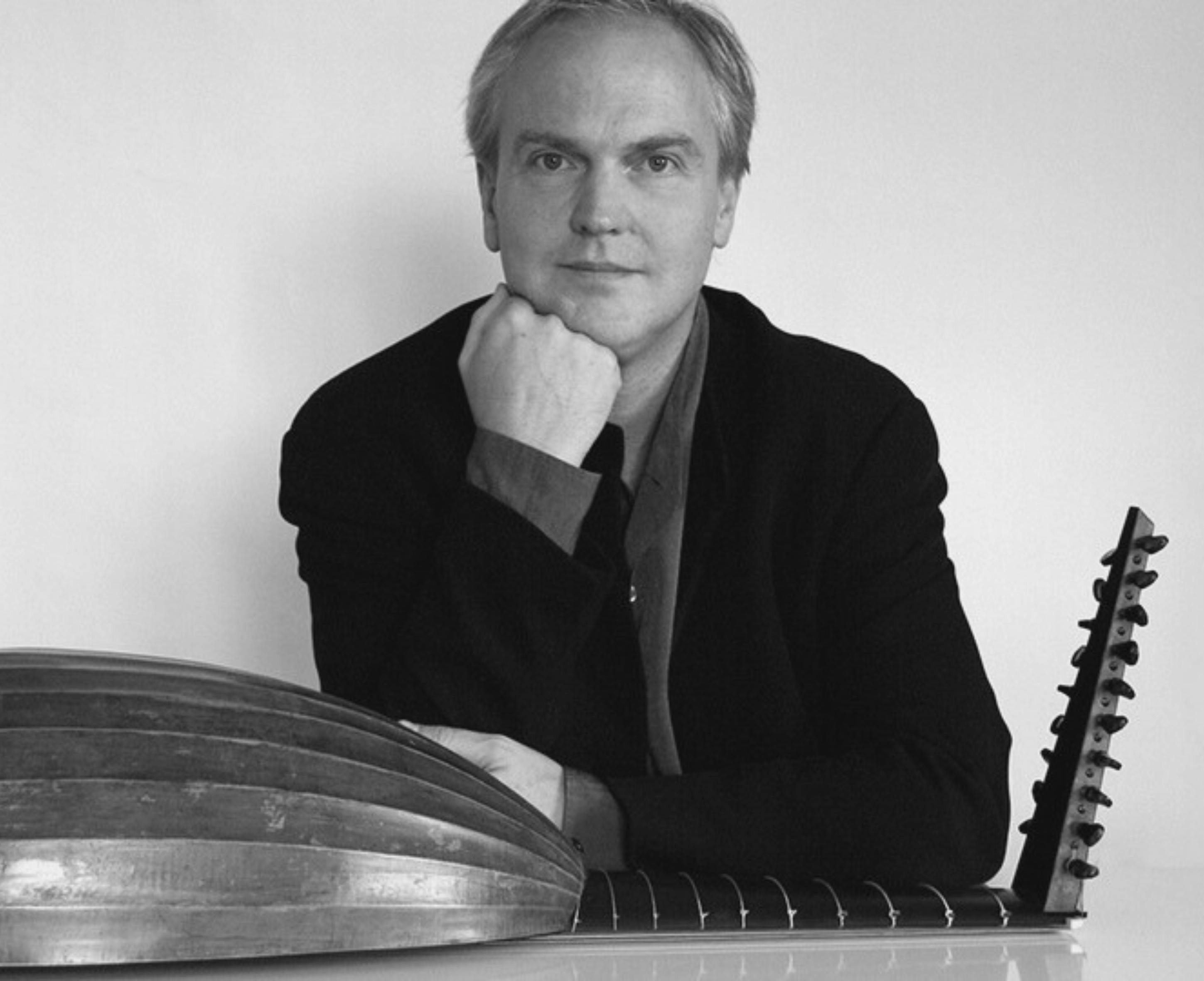 Black and white photo of a man with a lute on his lap