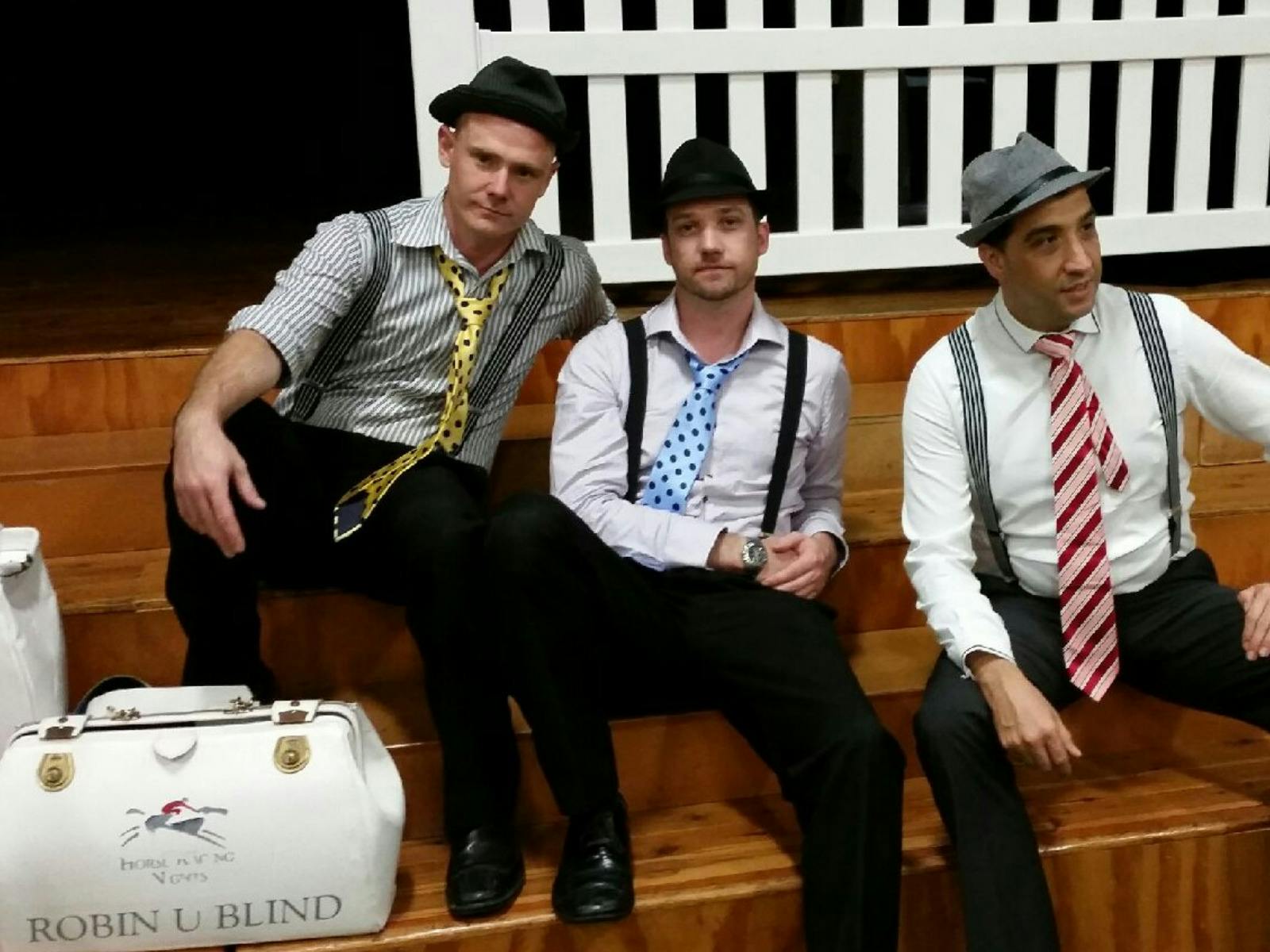 men dressed as bookies posing seated on wooden stairs