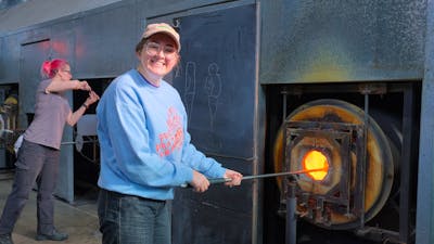 Participant in the Glassworks hotshop working with molten glass