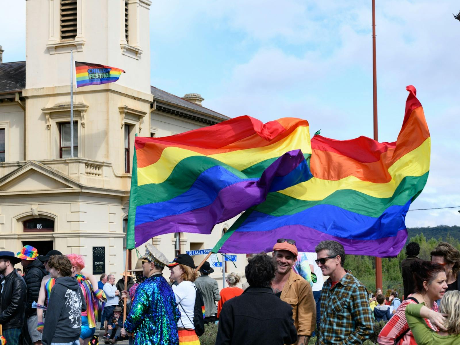 rainbow flags fly in the wind in front of historic building in Daylesford town centre