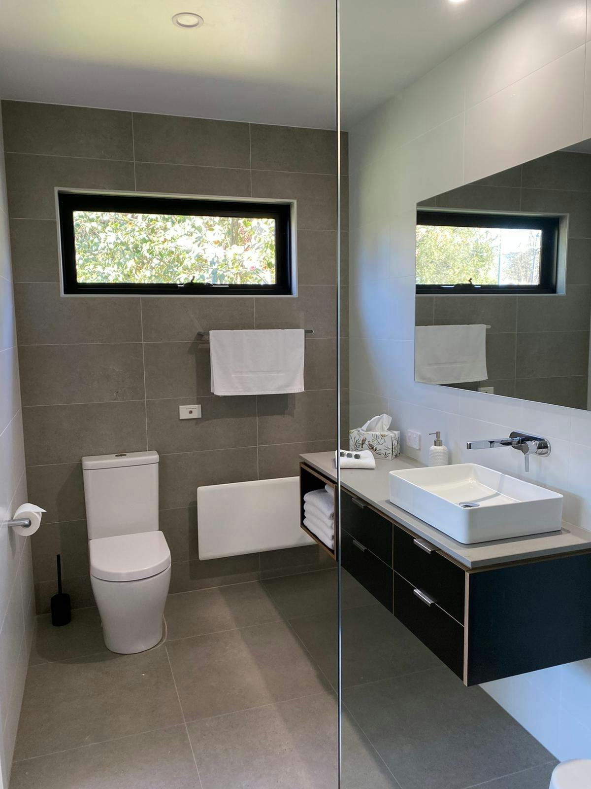 Modern bathroom with plush towels, toiletries and generous walk-in shower. Nobo wall heater.