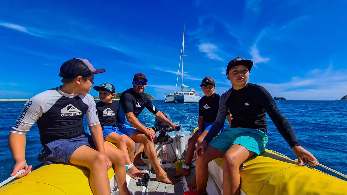 Kids operating outboard tender exploring Whitsunday Islands
