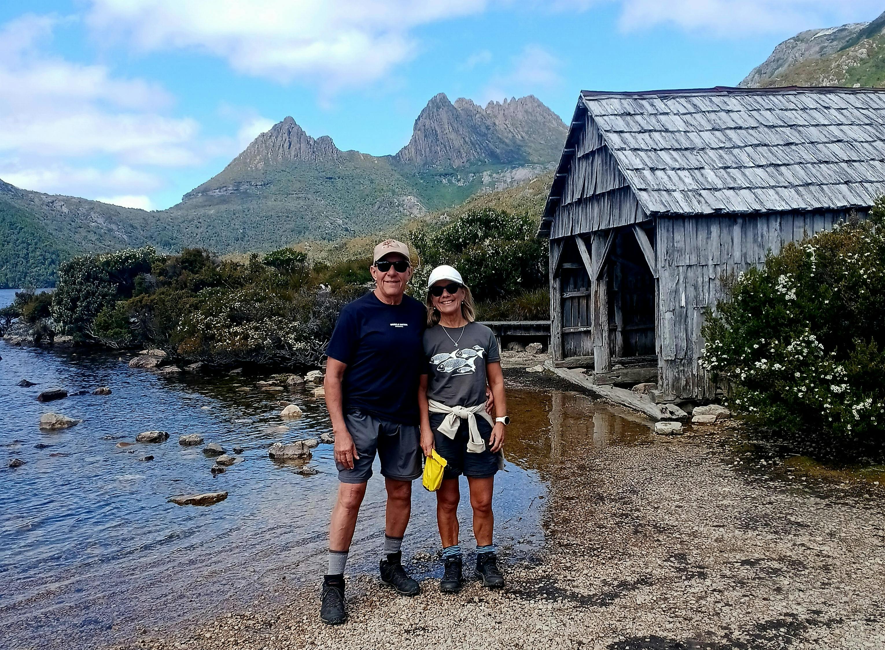 Couple standing near the Dove Lake Boatshed with Cradle Mountain in the background Tasmania.