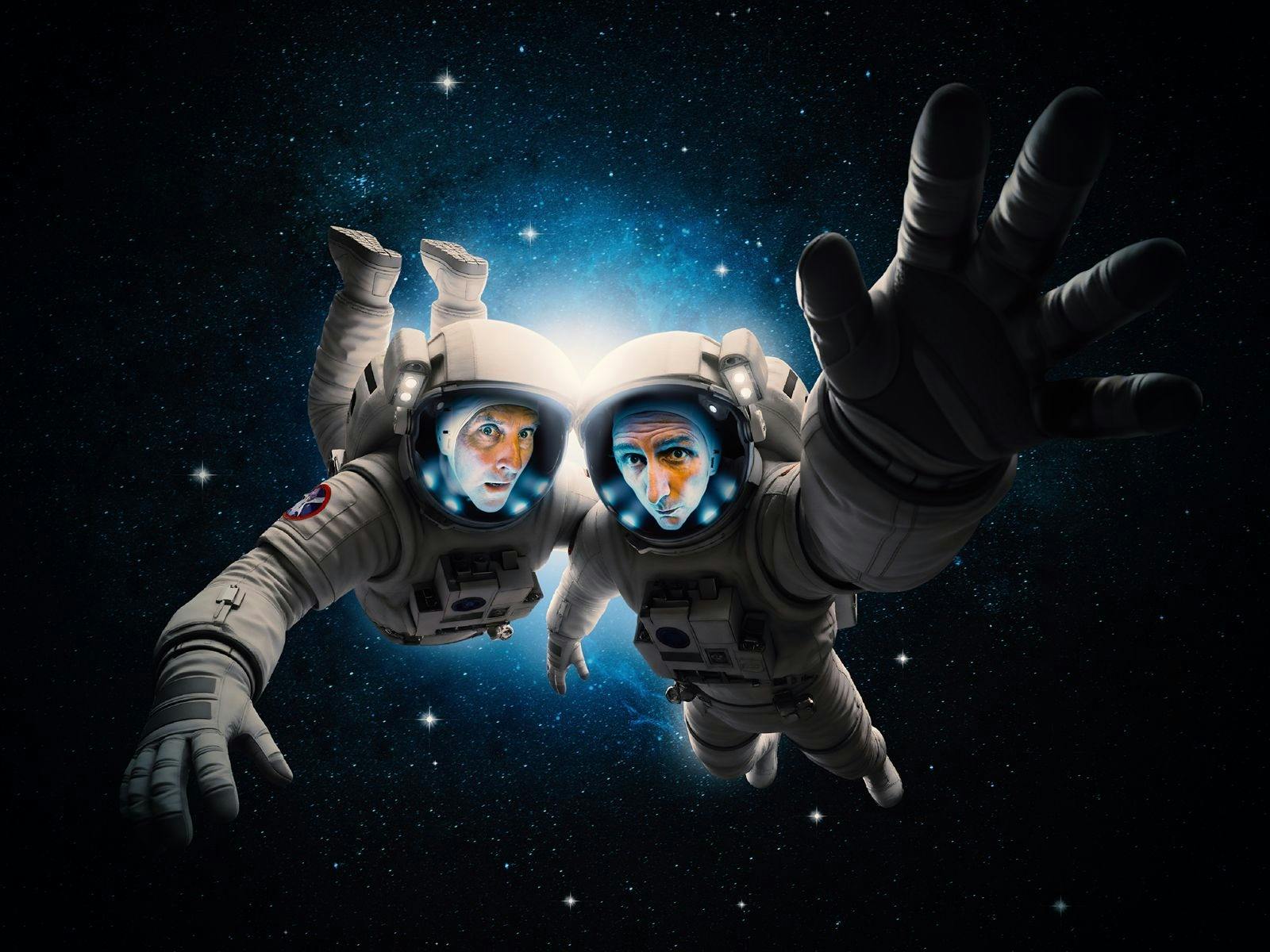 Two men in space suits floating in space.