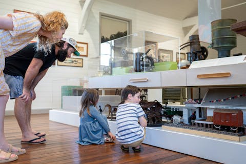 Two children looking at models of buildings with their parents looking on.