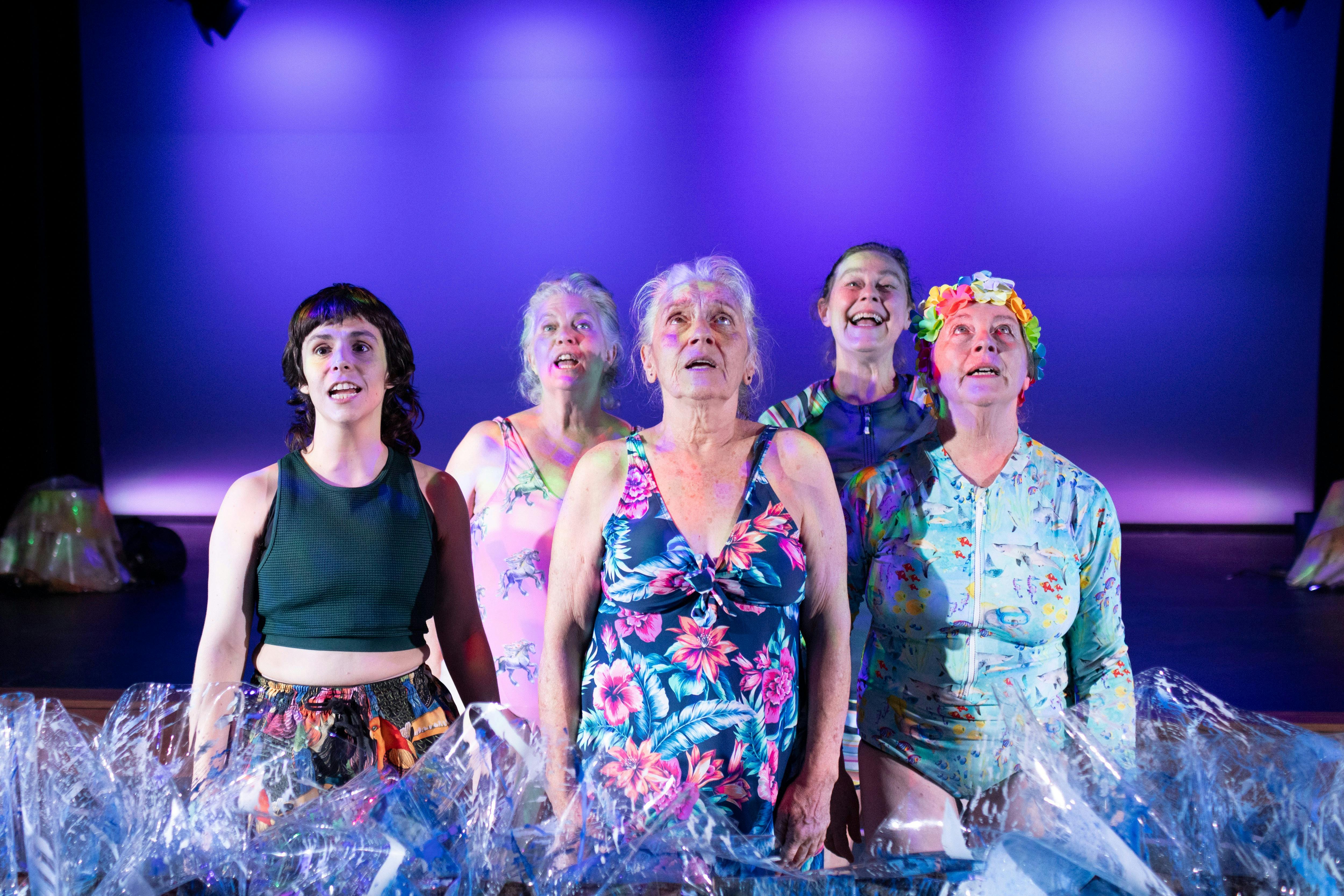 Group of 5 people on stage singing in bathers