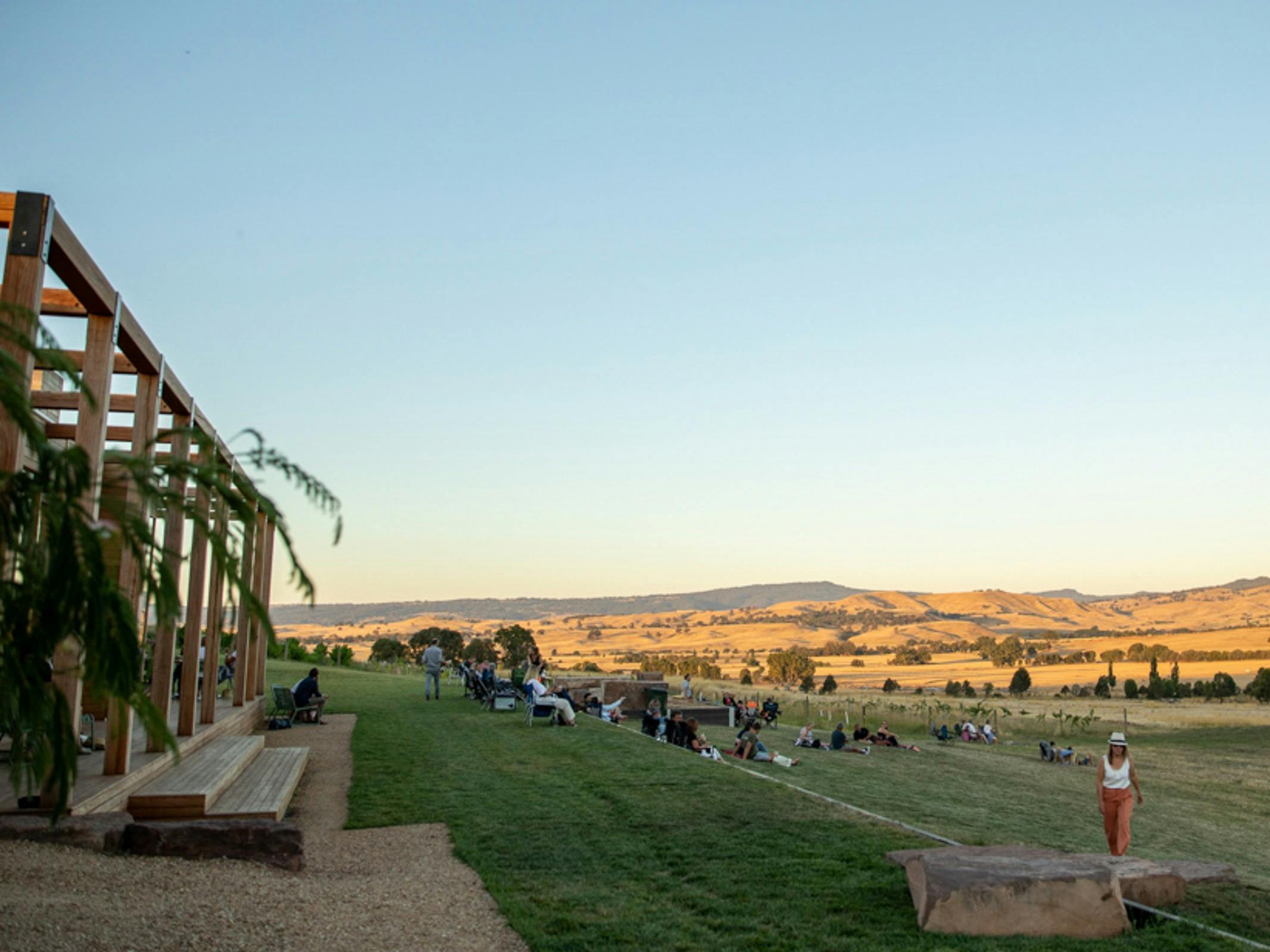 Sunset view looking over the cellar door with people relaxing on the lawn