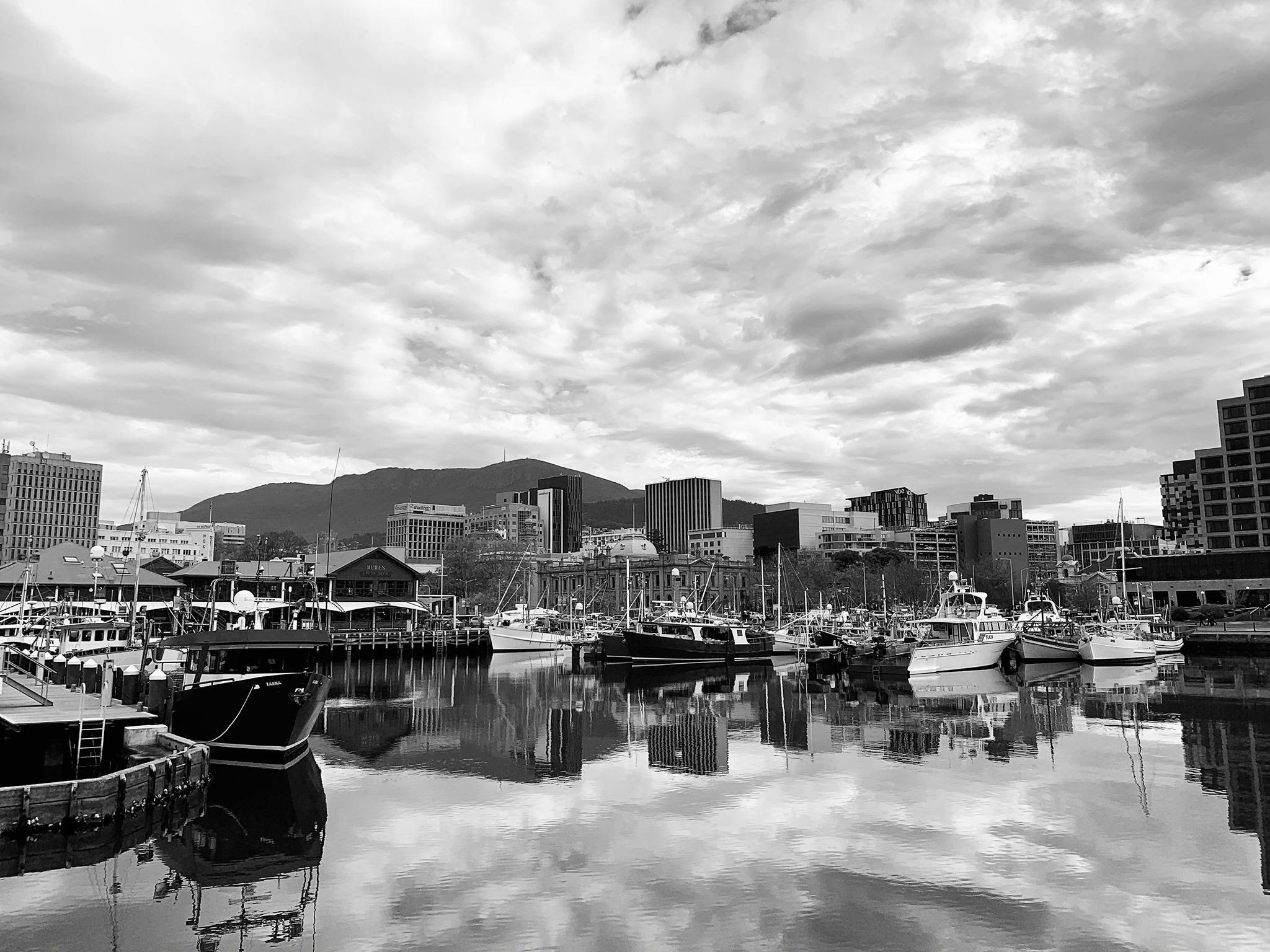 Photo of river Derwent with buildings in the city being visible and the mountain  in the background