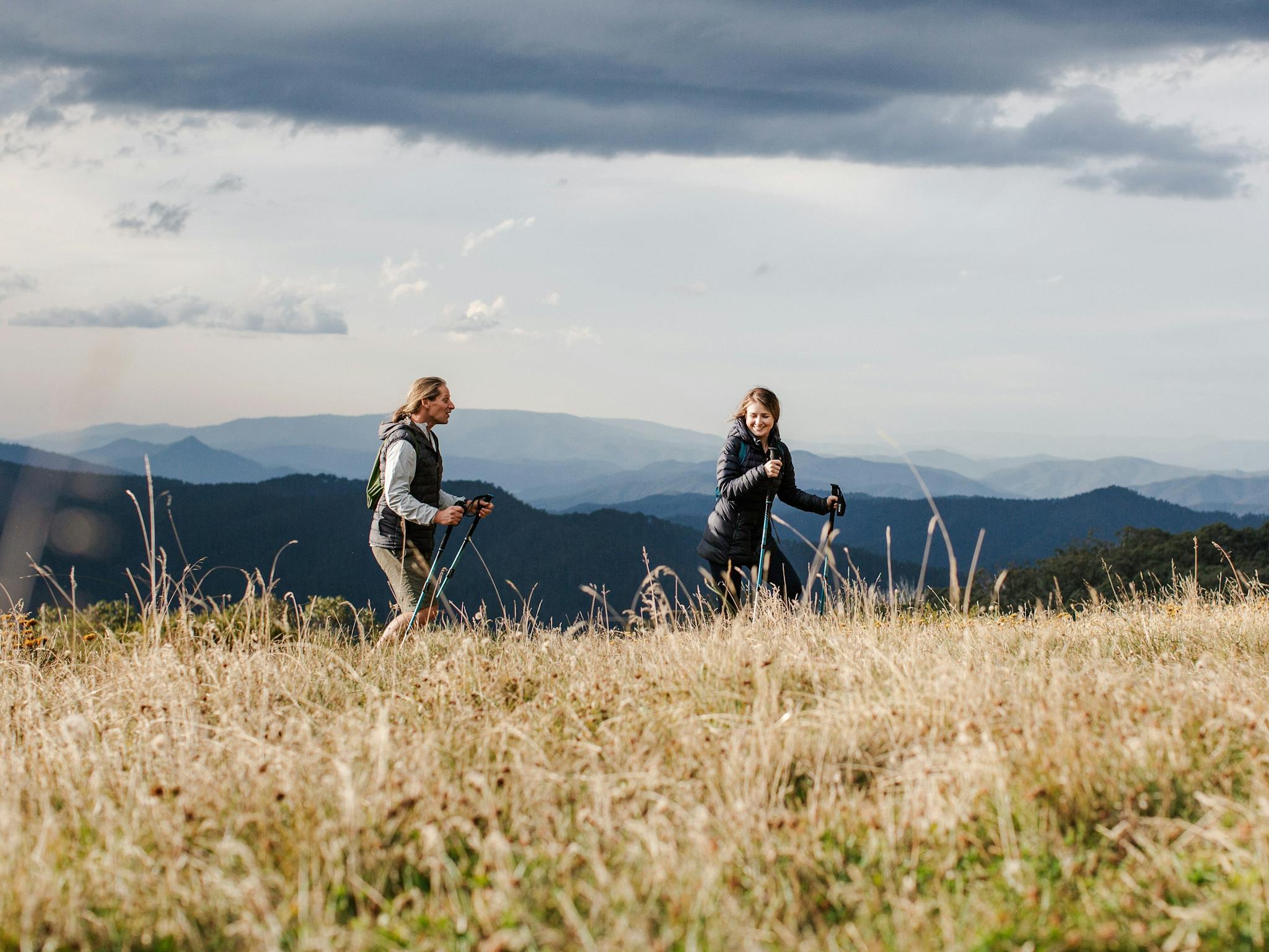 Couple of hikers on top of Clear Hills with mountain range stretching in the background.