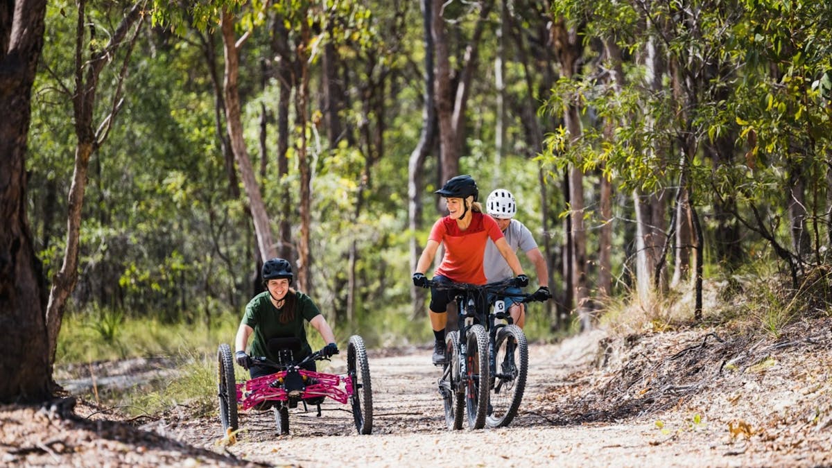 ATP mountain biking and accessibility riders on dirt tracks through bushland reserve