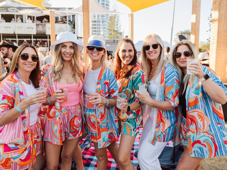 6 girls stand facing the camera holding a beer each, all in matching outfits