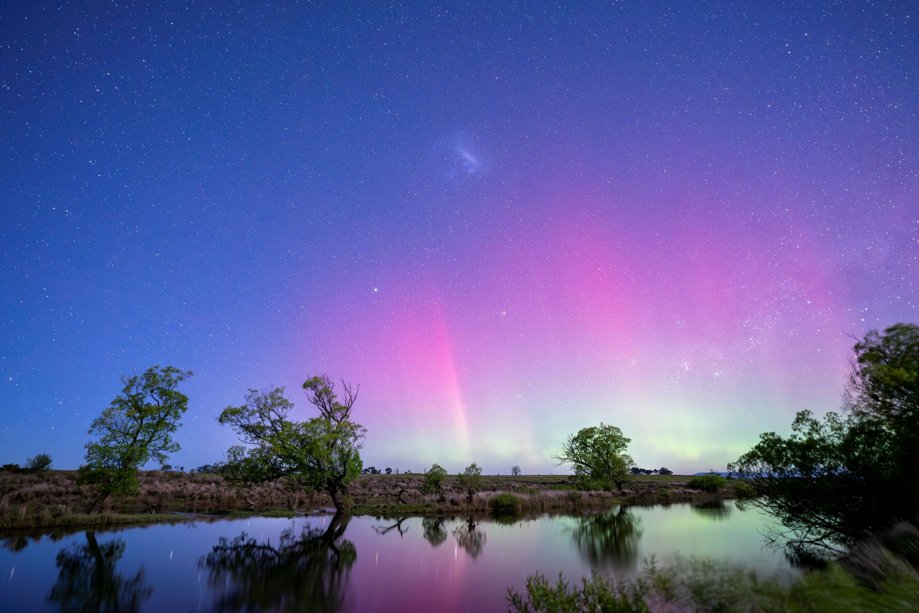 Stunning pink, purple and green glow of the Aurora Australis reflecting in the South Esk River.