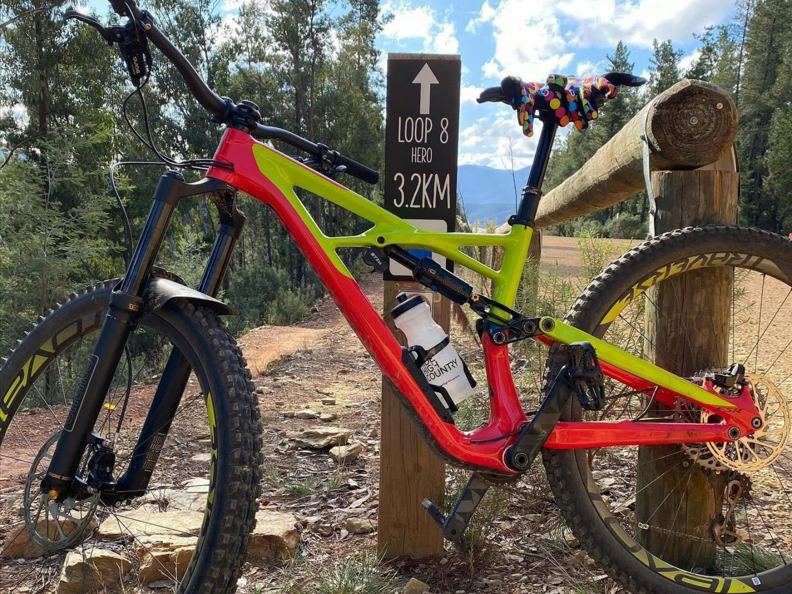 A red and yellow bike leans against a post at the top of the mountain bike trail.