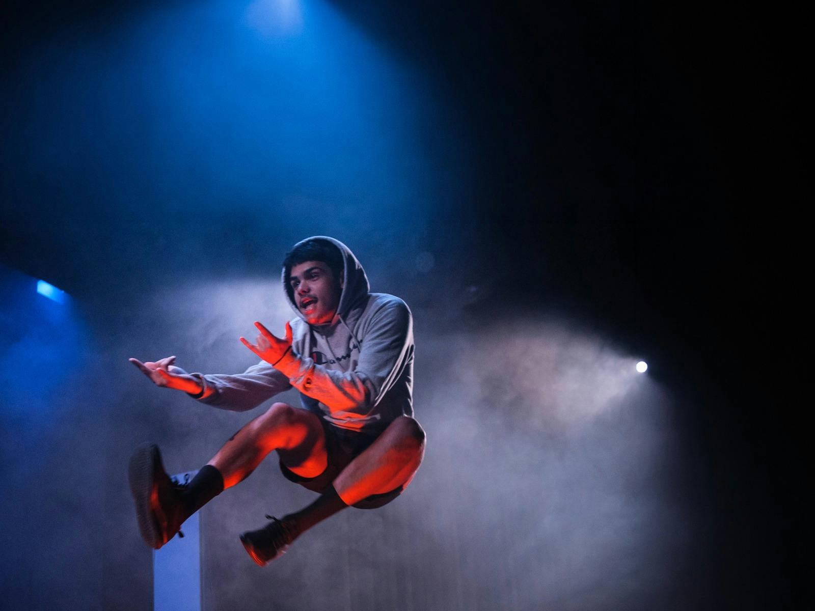 A young man in a grey hoodie jumping in the air A young man in a grey hoodie jumping in the air