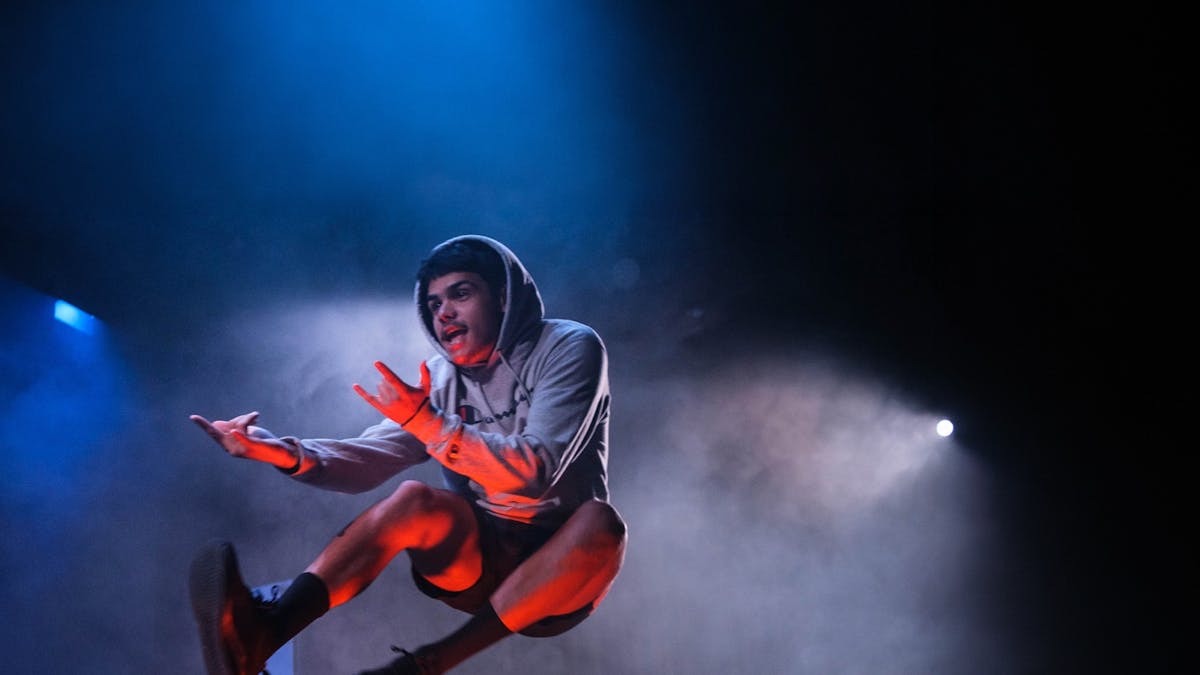 A young man in a grey hoodie jumping in the air