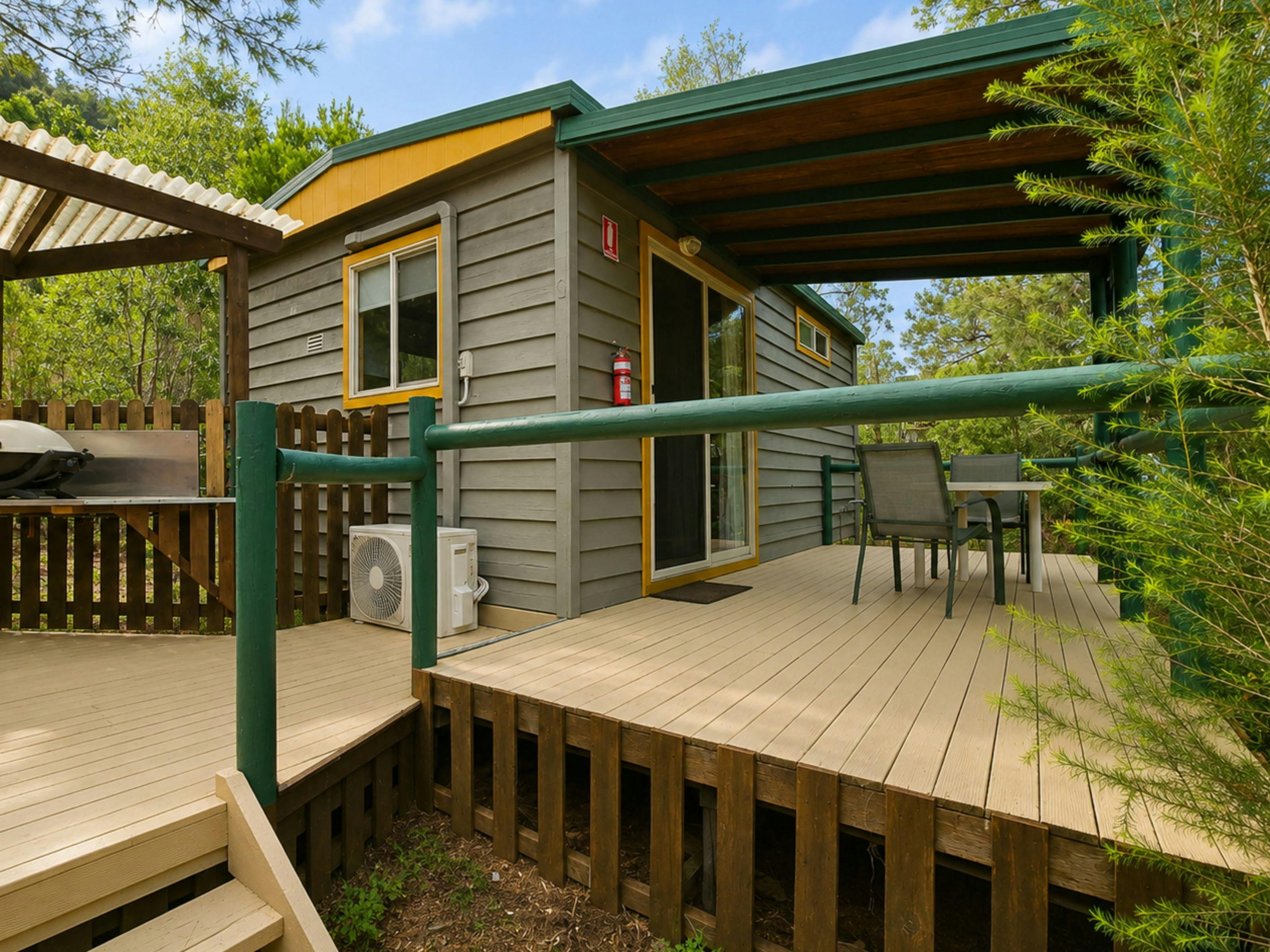 Exterior of the Cedar Bush Cabins featuring a deck with tables and chairs and a BBQ area.