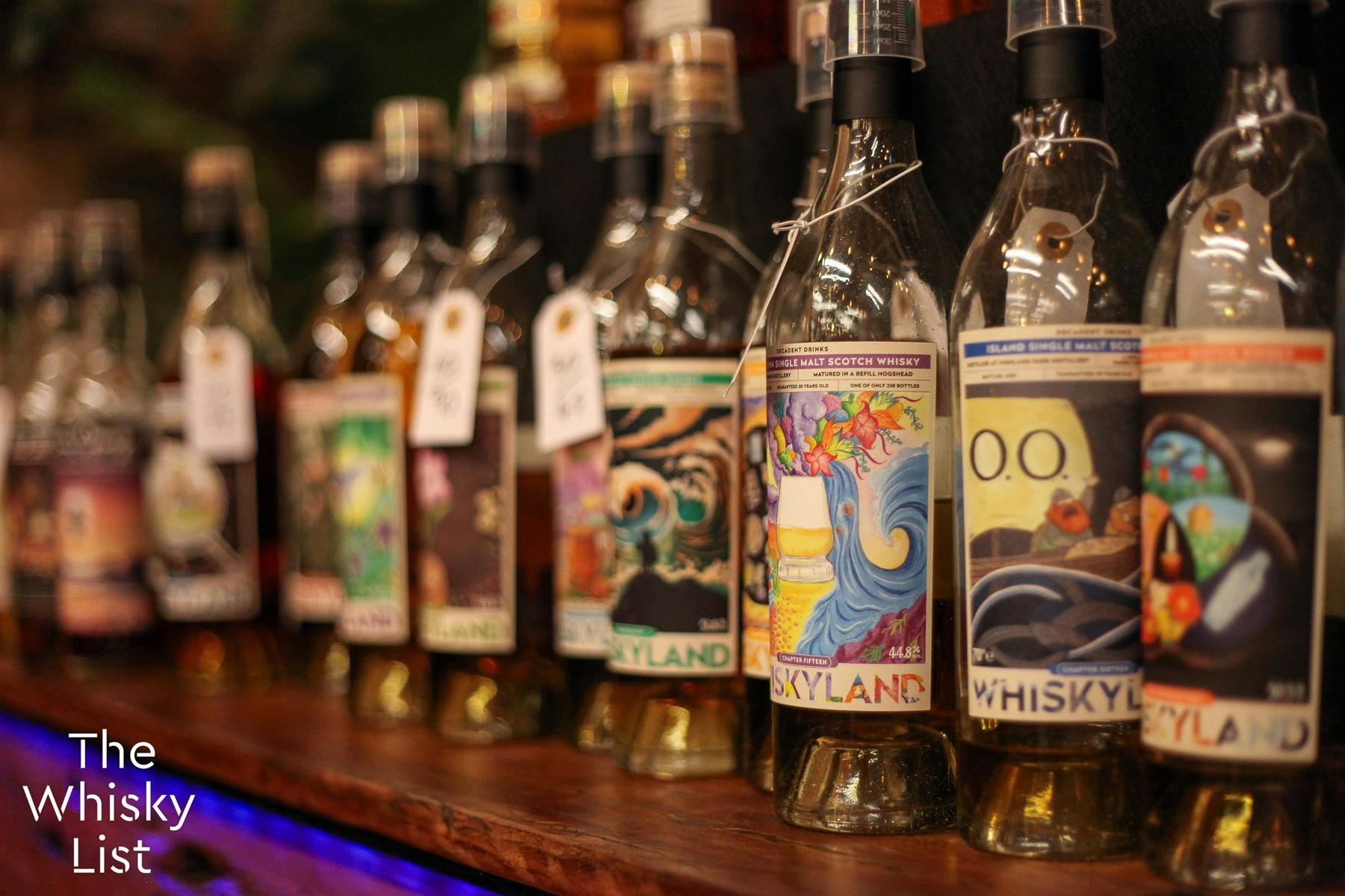 A long line of bottles with colourful artworks. Each with a swing tag for sample prices