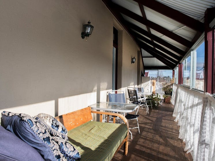 The glassed-in veranda with a day-bed, chairs and tables in the sun, available for guest use