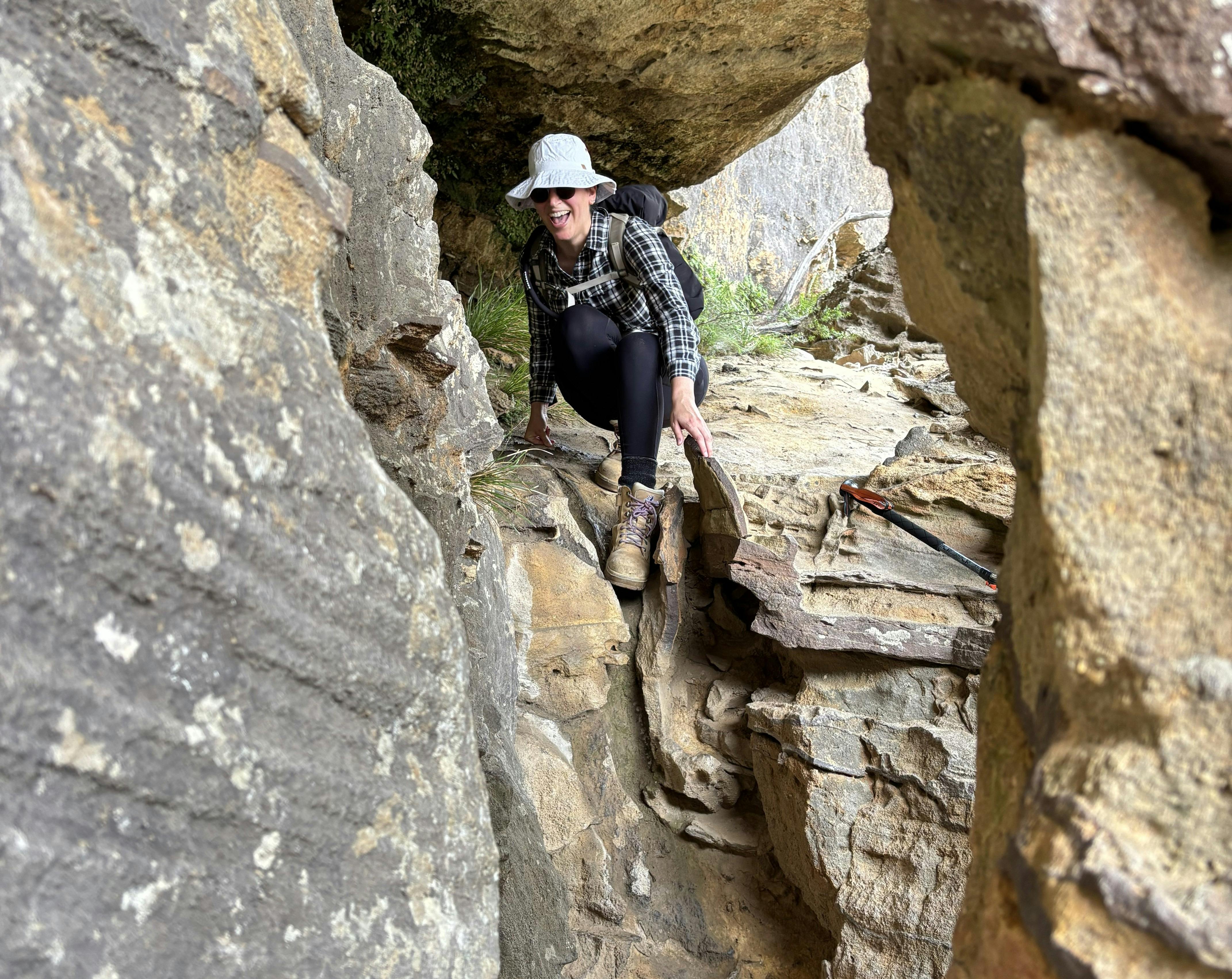 A woman climbing down a rock face in order to enter Darks Cave  in the Blue Mountains.