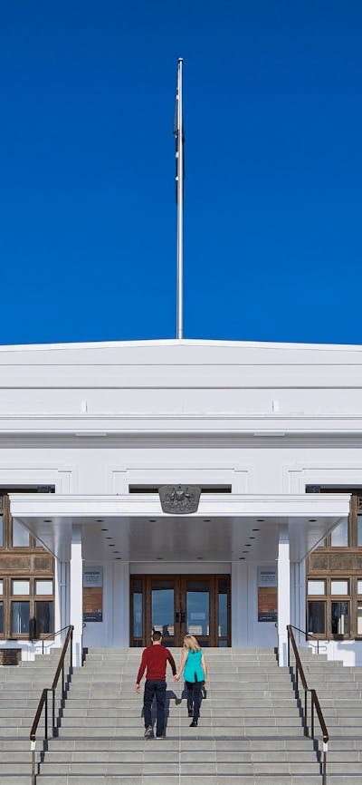 Two people walk up the steps of Old Parliament House