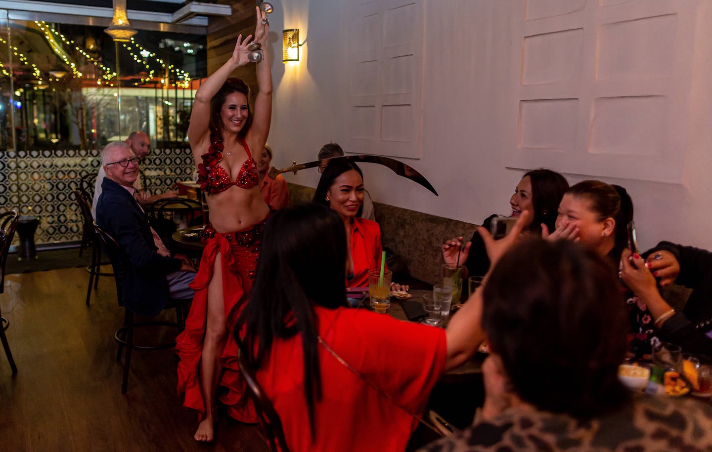 Belly dancer performing at Bar Beirut. She is balancing a sword on a seated customer's head.