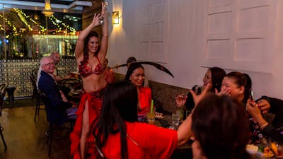 Belly dancer performing at Bar Beirut. She is balancing a sword on a seated customer's head.