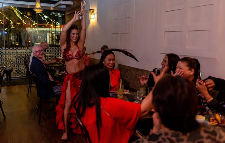 Belly dancer performing at Bar Beirut. She is balancing a sword on a seated customer's head.