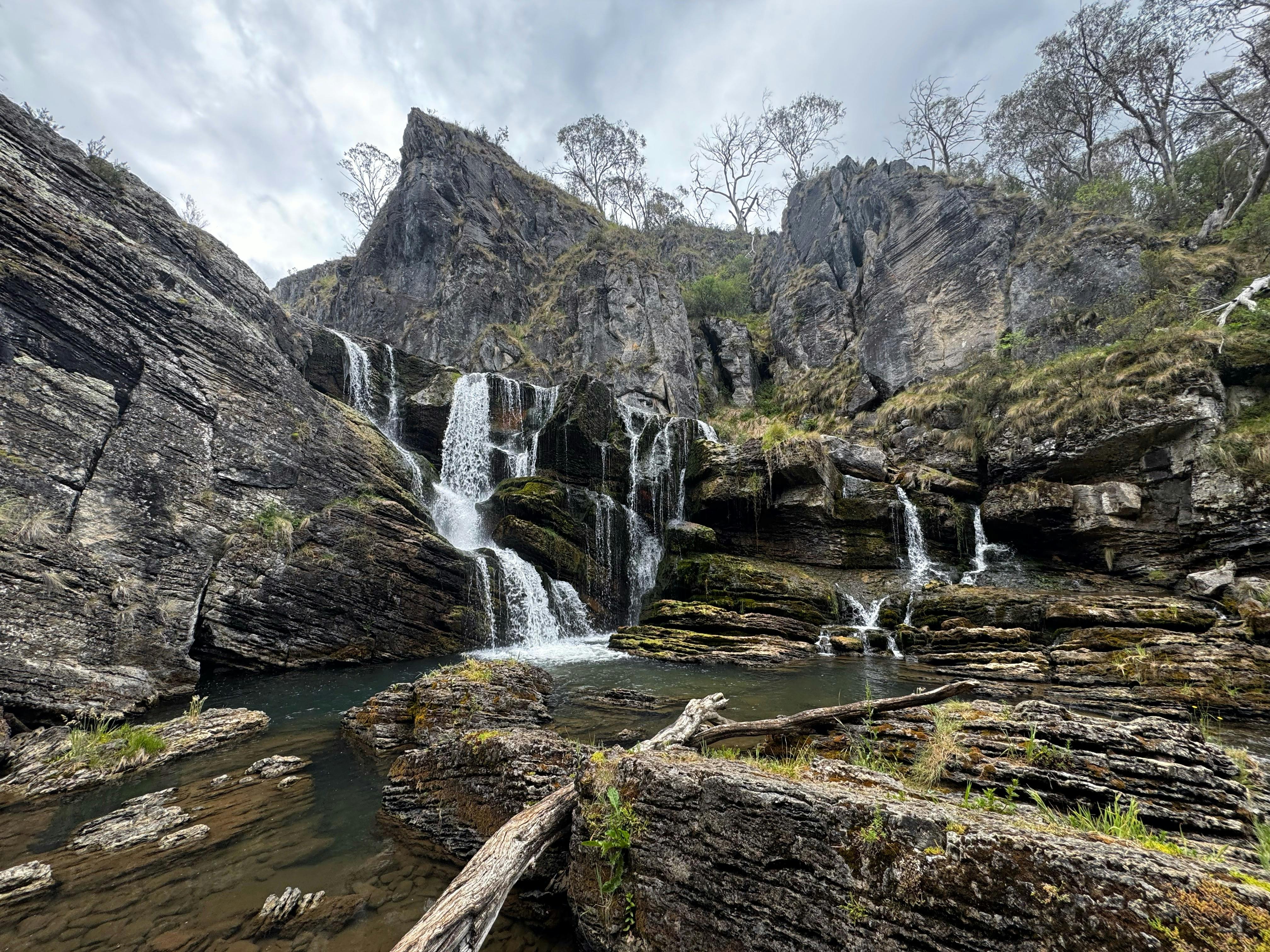 A waterfall leading into a pool of water with some rocks.