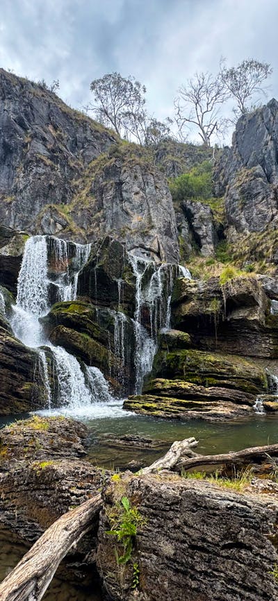 A waterfall leading into a pool of water with some rocks.