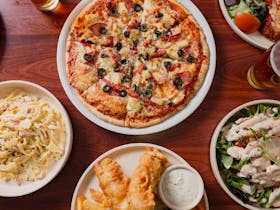 A table spread including pizza, pasta, fish and salad.