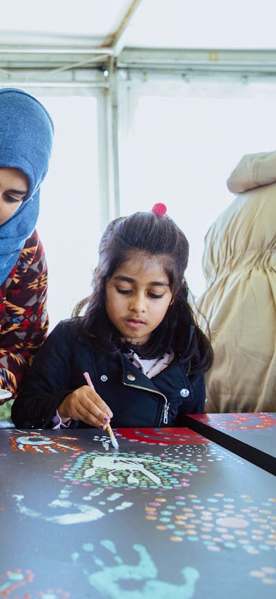 Family of four painting on large canvas decorated with colourful patterns and handprints