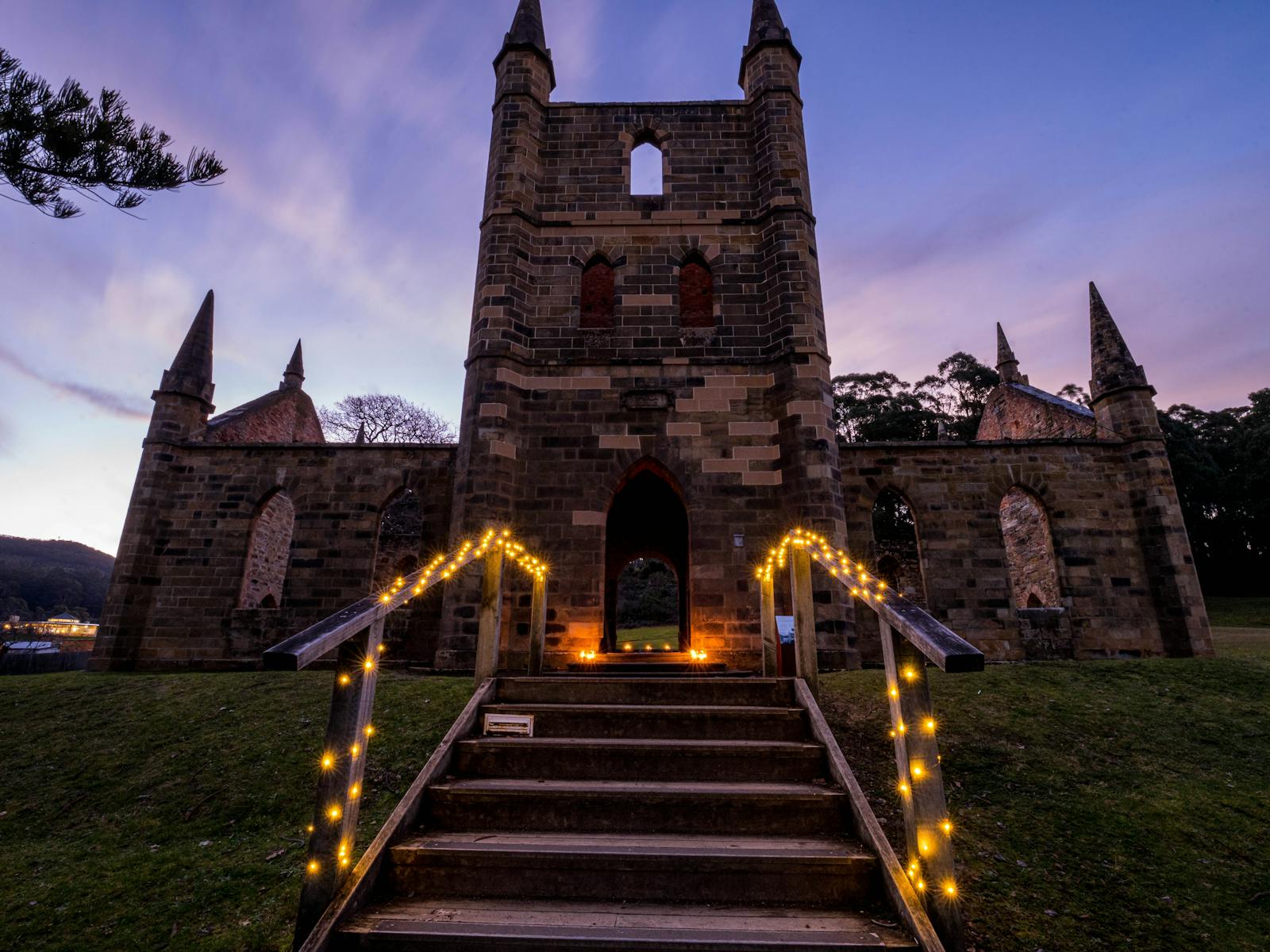 A closer look of Convict Church that is lit by lights under the purple and dark blue sky at dusk