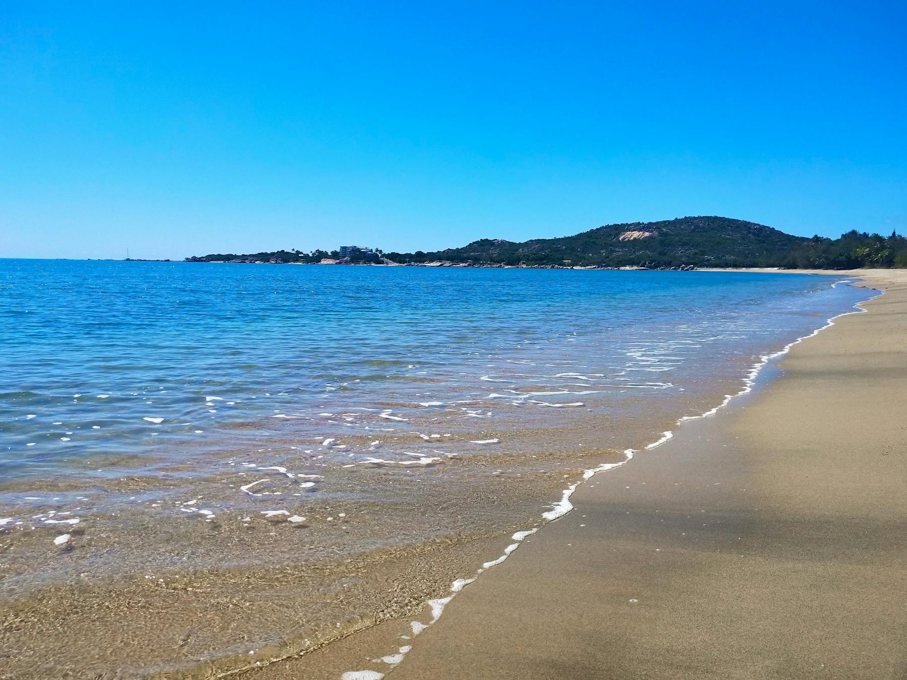 long sandy beach, sheltered blue bay and distant headland