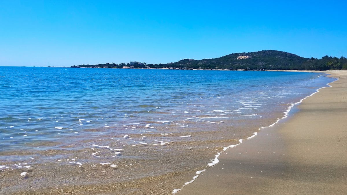 long sandy beach, sheltered blue bay and distant headland