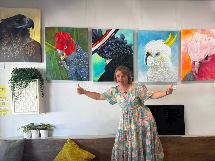 Artist standing with her bird paintings