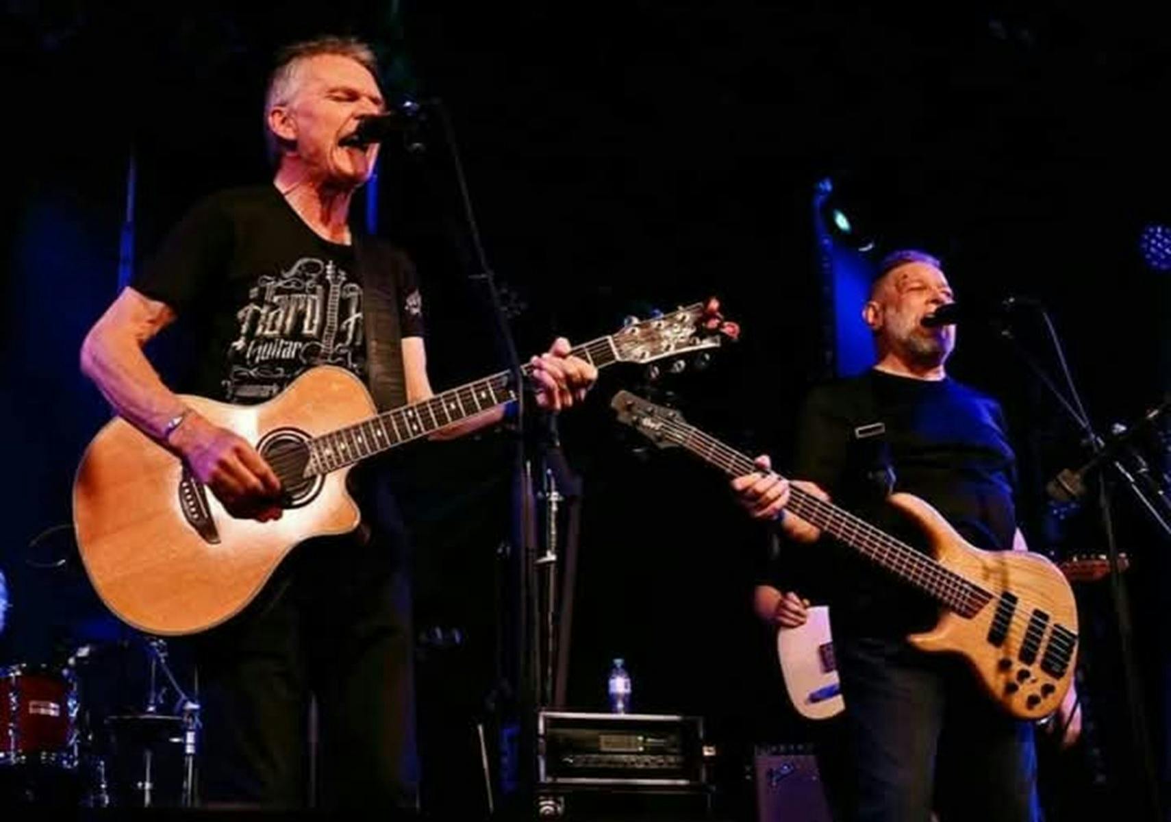 Two people singing with guitars on stage