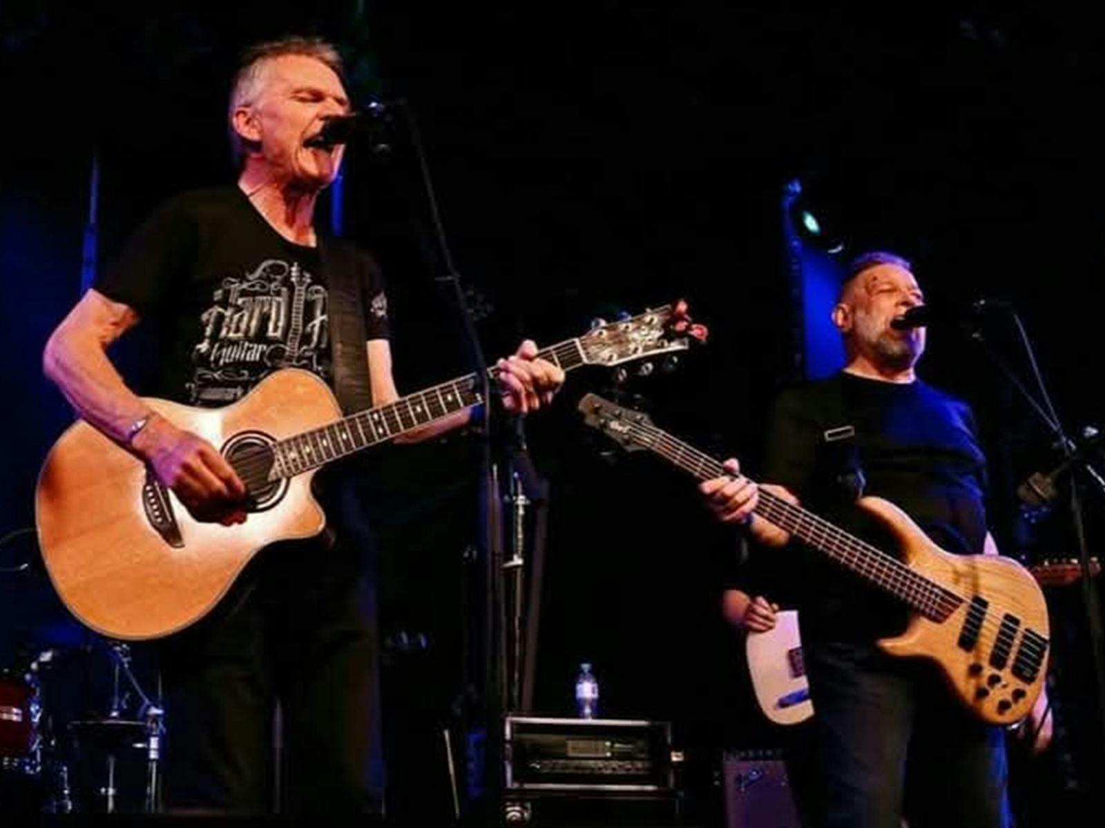 Two people singing with guitars on stage